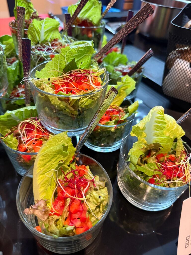Frische Salatportionen in Glaesern mit Blattsalat Tomaten und roten Sprossen
