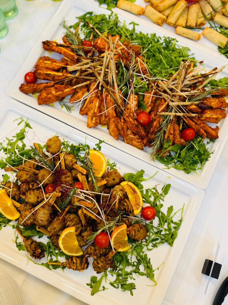 Gegrillte Fleischspiesse auf Ruccola mit Tomaten Orangen und Fruehlingsrollen